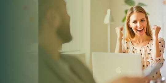 Our offers banner. Younf woman excited about results on her computer screen